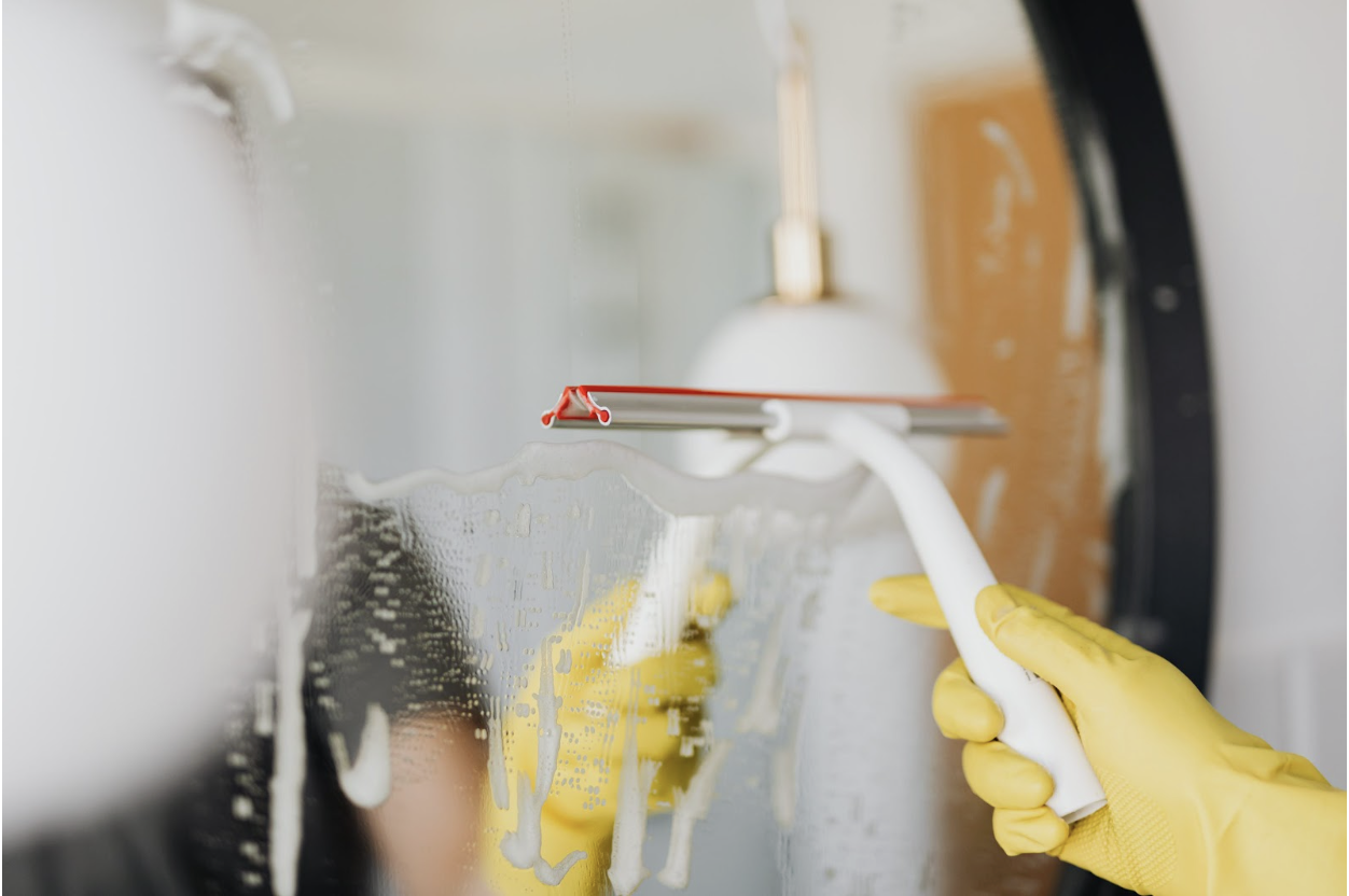 A person cleaning a mirror